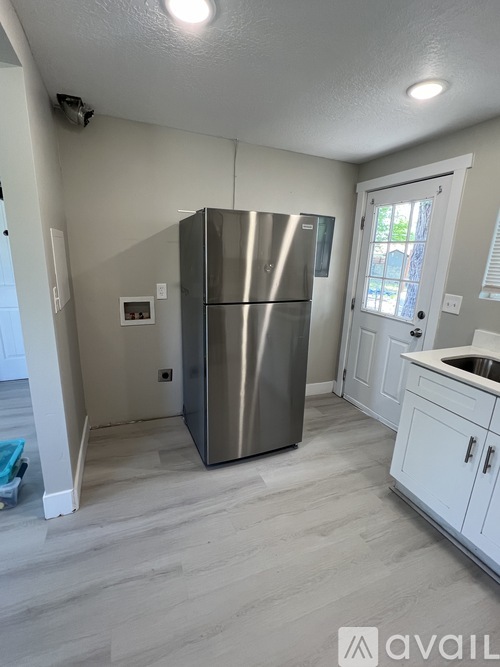 A kitchen with a stainless steel refrigerator and white cabinets.