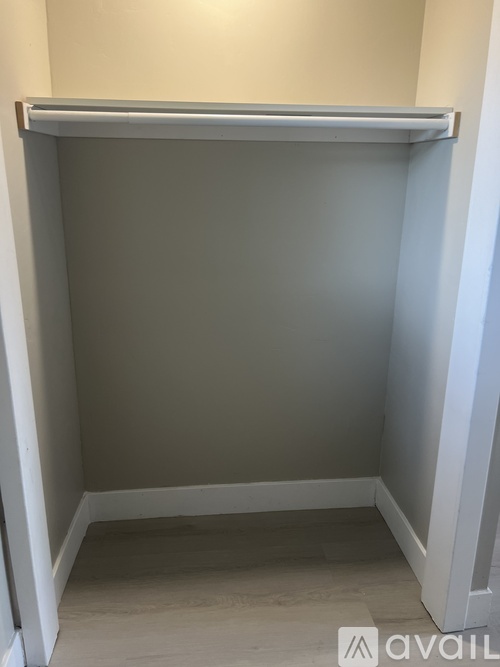 A small, empty room with a white door and a grey wall.