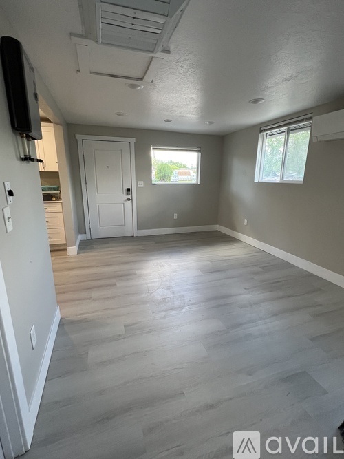 A spacious room with wooden flooring and a ceiling fan.