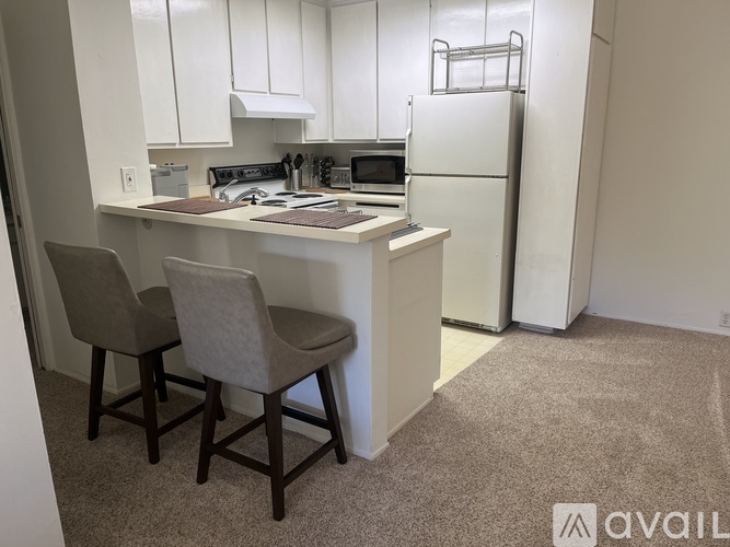 A kitchen with white cabinets and a white refrigerator.
