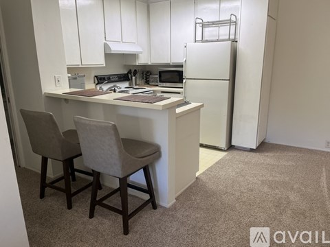 A kitchen with white cabinets and a white refrigerator.