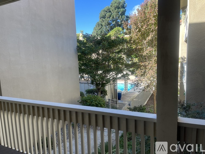 A balcony with a view of a pool and trees.