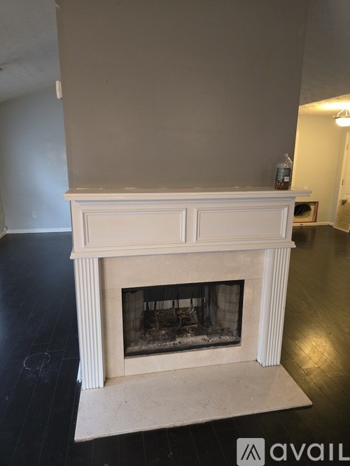 A white fireplace with a black grate in the middle.