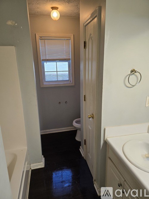 A bathroom with a toilet, sink, and window.