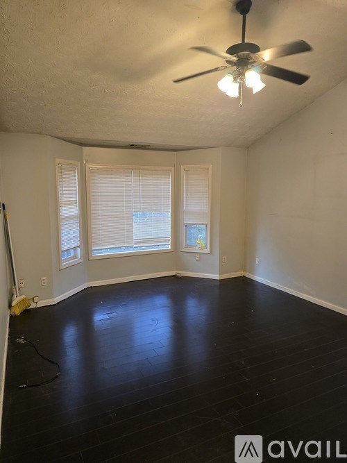 A room with a ceiling fan and a painting on the wall.