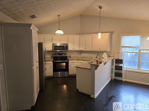 A kitchen with white cabinets and black countertops.