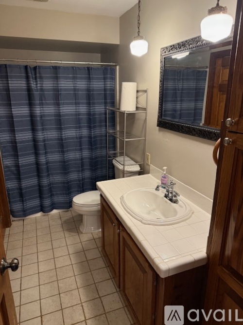 A bathroom with a white sink and a blue shower curtain.