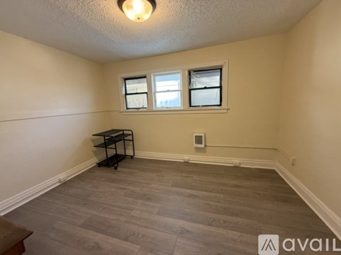 A room with a wooden floor and a window with blinds.