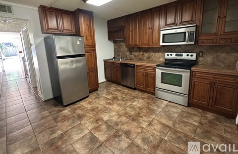 A kitchen with brown cabinets and a tile floor.