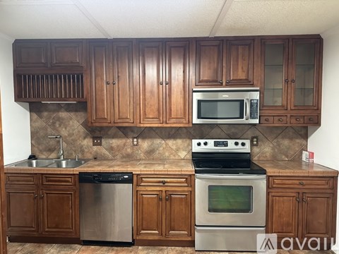 A kitchen with wooden cabinets and a stainless steel dishwasher.
