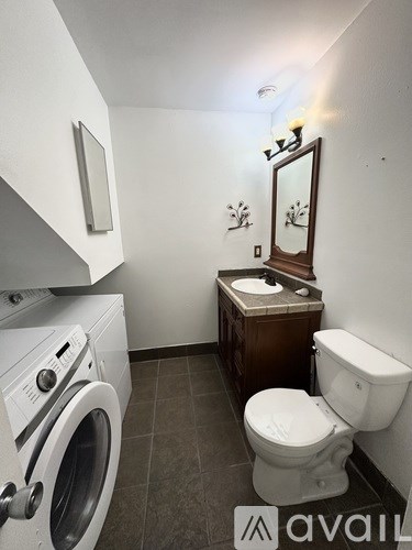 A small bathroom with a toilet, sink, and washing machine.