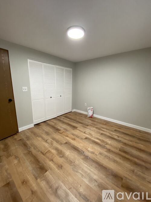 A room with wooden flooring and a white door.