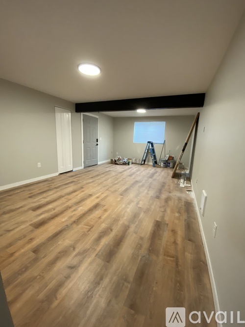 A room with wooden flooring and a window with blinds.
