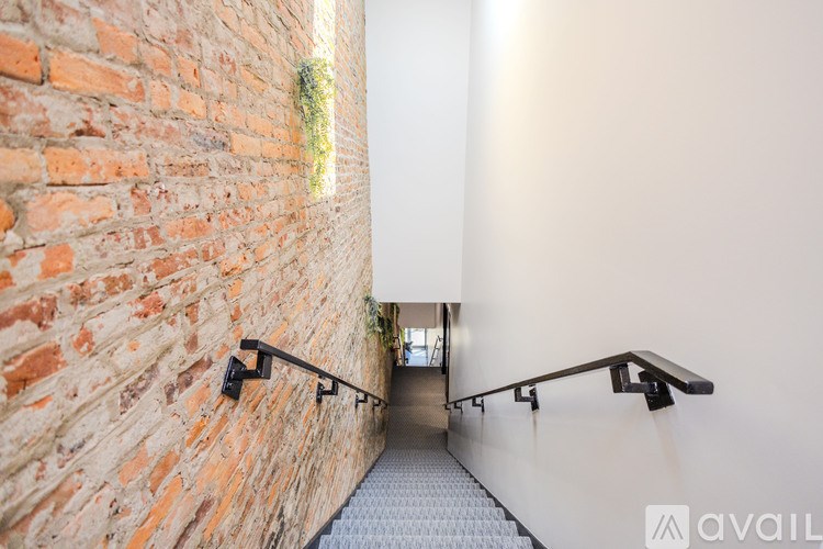 A staircase with a metal railing and a brick wall on the left side.