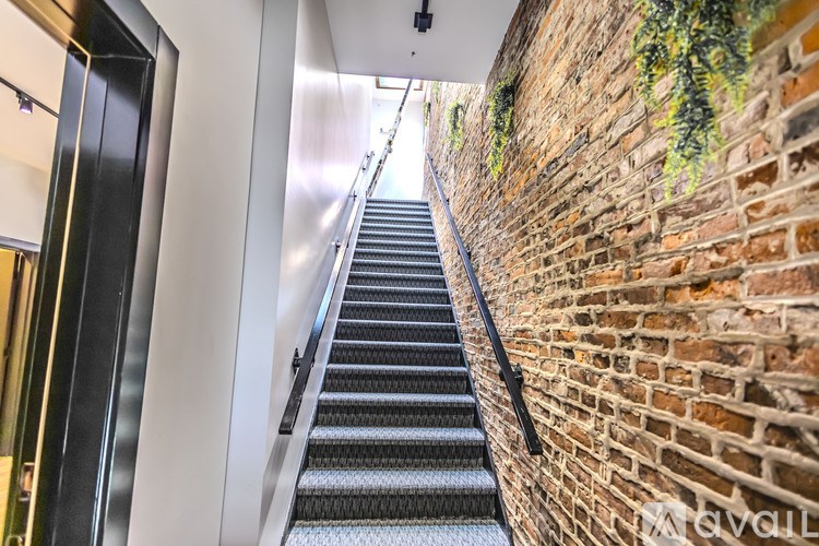 A staircase with a brick wall on one side and a metal railing.