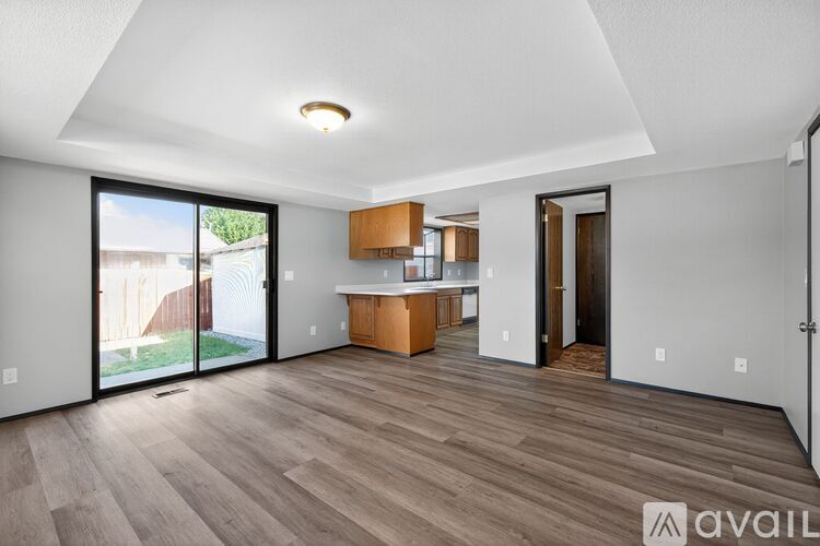 A spacious room with wooden flooring and a large window.