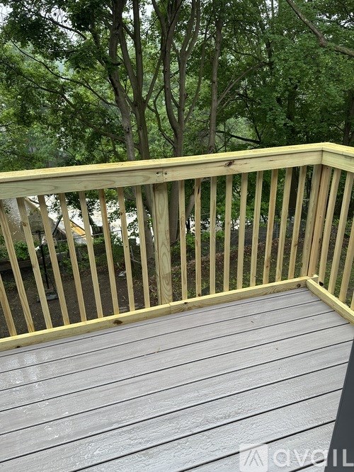 A wooden deck with a railing and trees in the background.