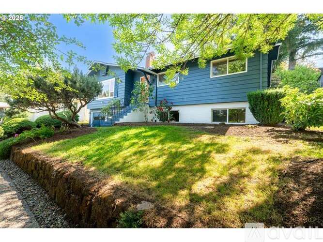 A blue house with a green lawn and trees in the background.