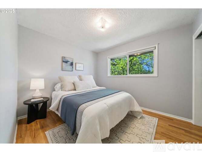 A bedroom with a bed, nightstand, and window.