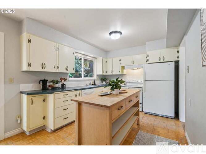 A kitchen with white cabinets and a wooden island.