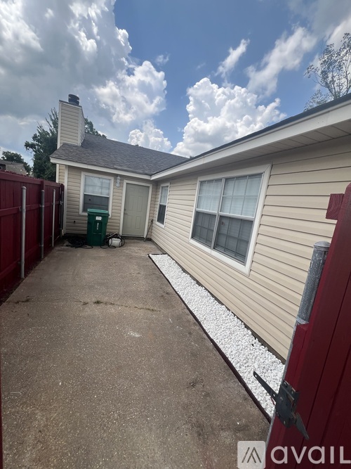 A house with a red fence and a green trash bin in front.