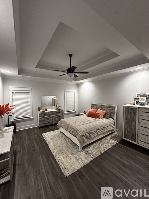 A bedroom with a large bed, a dresser, and a ceiling fan.