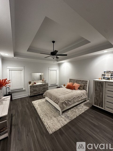 A bedroom with a large bed, a dresser, and a ceiling fan.