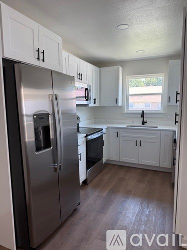 A kitchen with a stainless steel refrigerator and white cabinets.