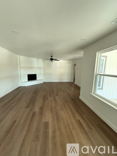 A room with wooden flooring and a window on the right side.