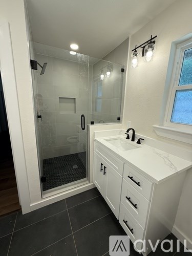 A bathroom with a walk-in shower and a vanity with a sink.