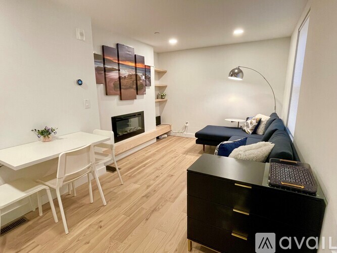 A modern living room with a white dining table and a black sofa.