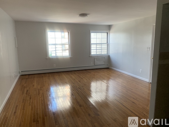 A room with wooden floors and two windows.