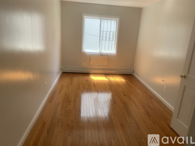 A room with wooden flooring and a window letting in sunlight.