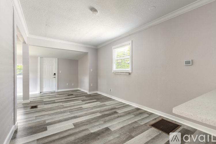 A spacious room with a wooden floor and a window with blinds.