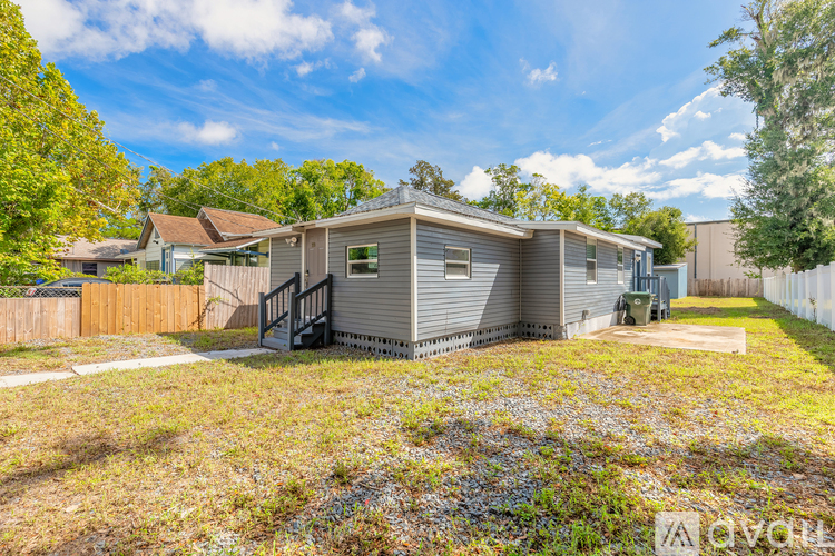 A mobile home sits in a grassy lot with trees in the background.