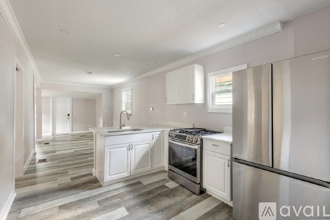 A modern kitchen with white cabinets and stainless steel appliances.
