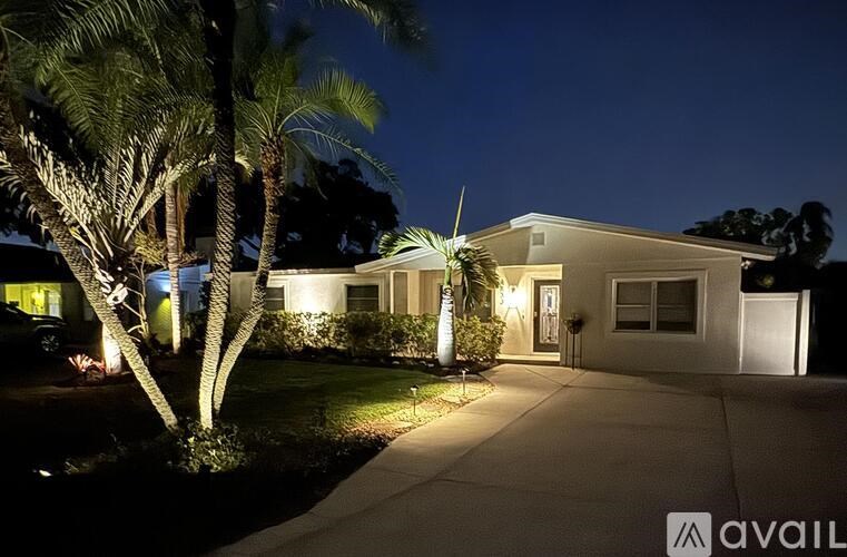A house with a driveway and palm trees in front.