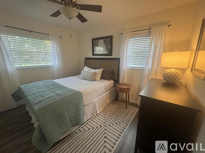 A bedroom with a bed, a ceiling fan, and a striped rug.