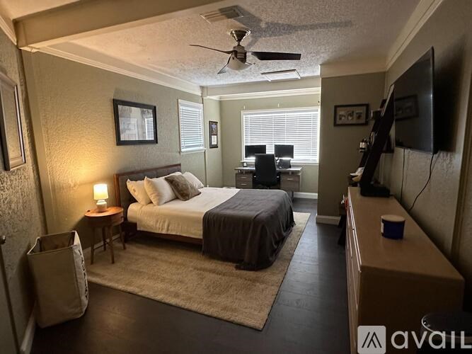 A bedroom with a bed, a ceiling fan, and a television.