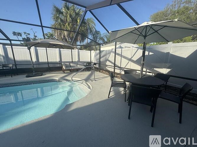 A pool area with a table and chairs under an umbrella.