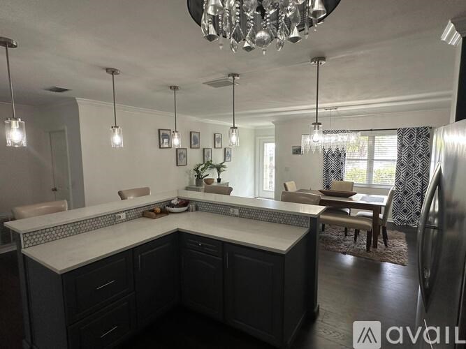 A modern kitchen with a large island and a chandelier.