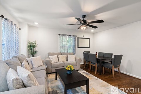 A living room with a grey couch, a coffee table, and a dining table set up.