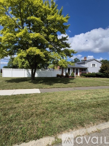 A brick pathway leads through a grassy area to a house.