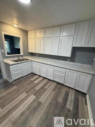 A kitchen with white cabinets and a wooden floor.