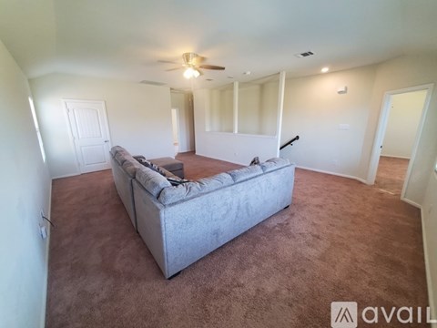A living room with a grey couch and a ceiling fan.