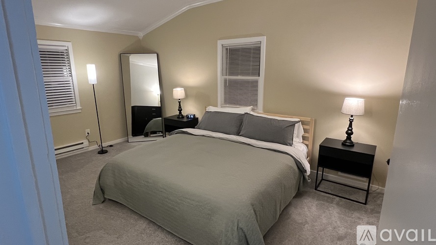 A bedroom with a large bed and two lamps.