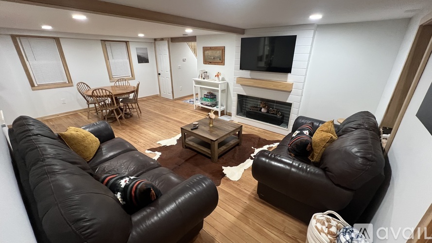 A living room with black leather couches and a fireplace.