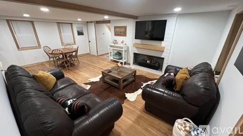 A living room with black leather couches and a fireplace.