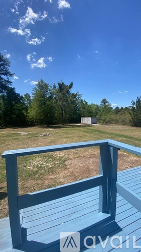 A blue deck with a view of a field and trees.