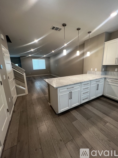 A kitchen with white cabinets and a wooden floor.